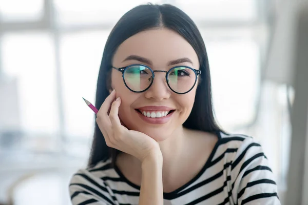 Mujer guapa de pelo oscuro con anteojos sonriendo amablemente — Foto de Stock