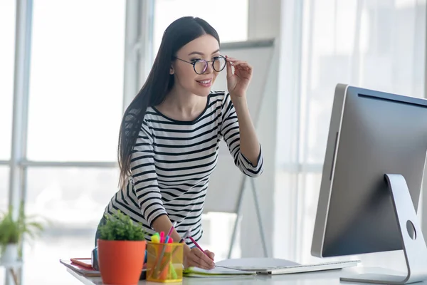 Mujer de cabello oscuro con una camisa a rayas mirando la pantalla de la computadora — Foto de Stock