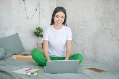 Koyu renk saçlı genç bir kadın video görüşmesi yapıyor ve gülümsüyor.