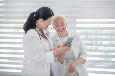 Pencerenin yanında duran beyaz önlüklü iki kadın..