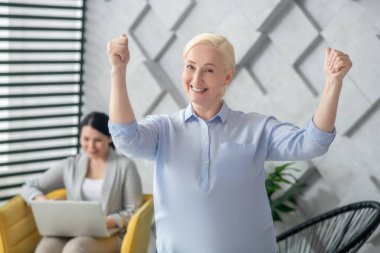 Elleri havada neşeli yetişkin bir kadın..