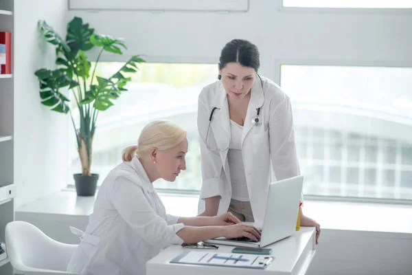 İki kadın doktor ekrana bakıyor ve ciddi görünüyorlar. — Stok fotoğraf