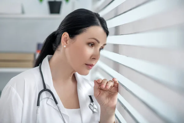 Succesvolle vrouw in witte medische jas bij het raam. — Stockfoto