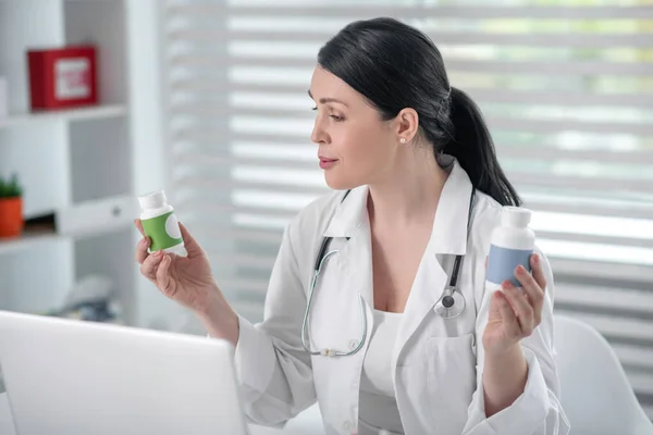 Mujer con abrigo blanco sosteniendo la medicina en sus manos . — Foto de Stock