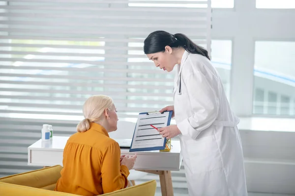 Médecin femme réussie debout près d'un patient assis . — Photo