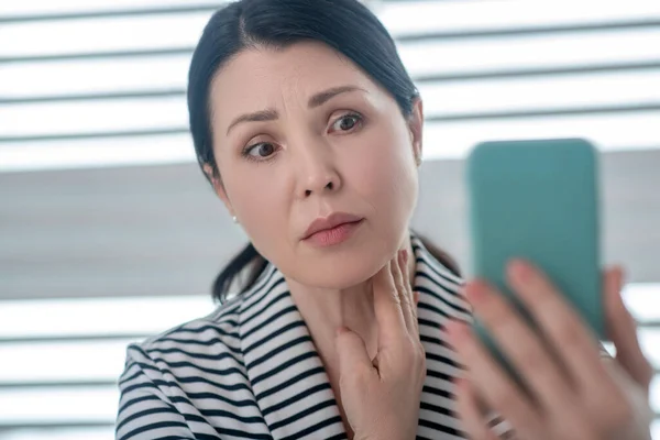 Mujer adulta ansiosa con un teléfono inteligente en la mano . — Foto de Stock