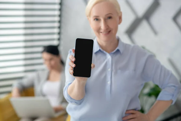 Radostná žena středního věku držící smartphone zobrazující obrazovku — Stock fotografie