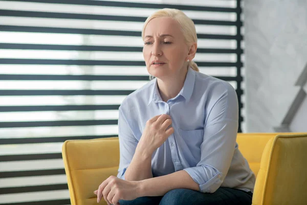 Sad adult woman sitting in a chair near the window. — Stock Photo, Image