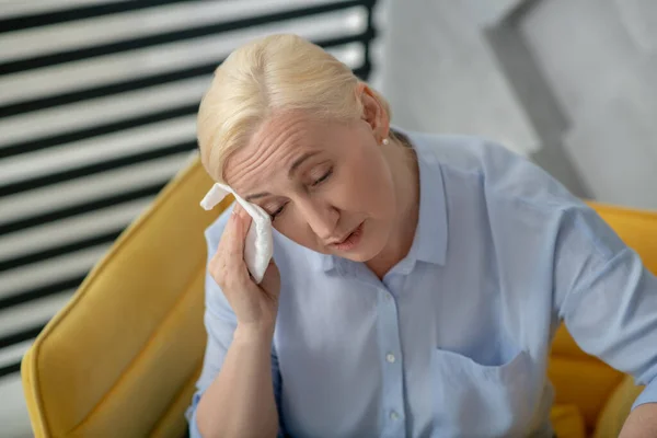 Woman blonde with closed eyes wiping her face with napkin. — Stock Photo, Image
