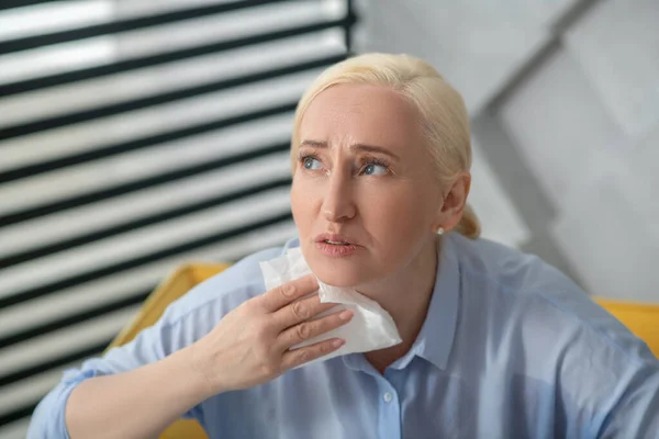 Mujer adulta infeliz con una toalla de papel cerca del cuello . — Foto de Stock