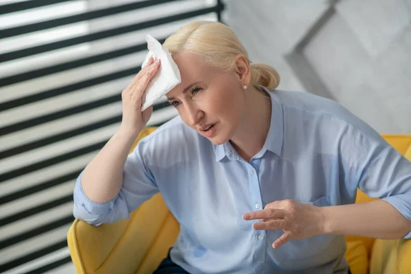 Adult woman with a napkin near her forehead — Stock Photo, Image