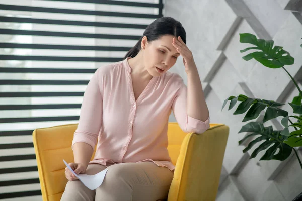 Mujer en blusa rosa y pantalones sentados en un sillón . — Foto de Stock