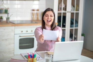 Pembe bluzlu genç bir kadın iş teklifinde bulunuyor ve mutlu görünüyor.