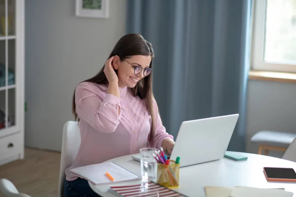 Mulher de blusa rosa usando óculos fazendo uma videoconferência — Fotografia de Stock
