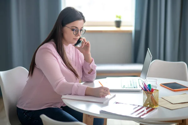 Kvinna i rosa blus med glasögon som har ett telefonsamtal — Stockfoto