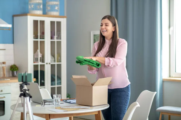 Joven morena sosteniendo pantalones verdes y sonriendo — Foto de Stock