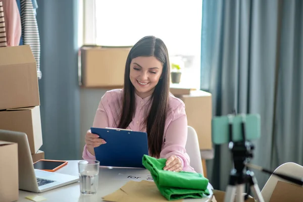 Mujer joven de cabello oscuro mirando la lista y sonriendo — Foto de Stock