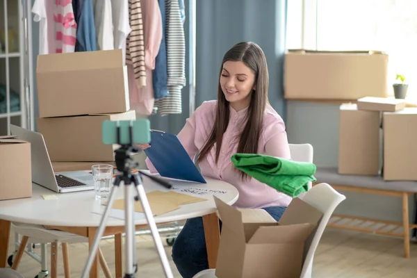 Mujer joven de cabello oscuro sentada a la mesa durante la venta en línea — Foto de Stock