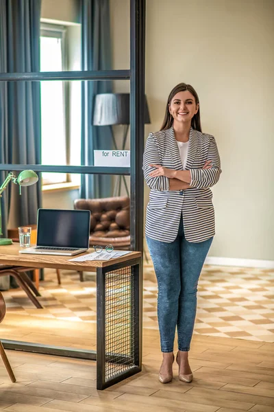 Mulher bonita de cabelos escuros em pé na mesa e sorrindo — Fotografia de Stock