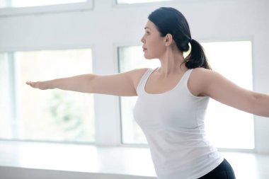 Esmer kadın. Savaşçı pozunda duruyor. Kolları yere paralel.