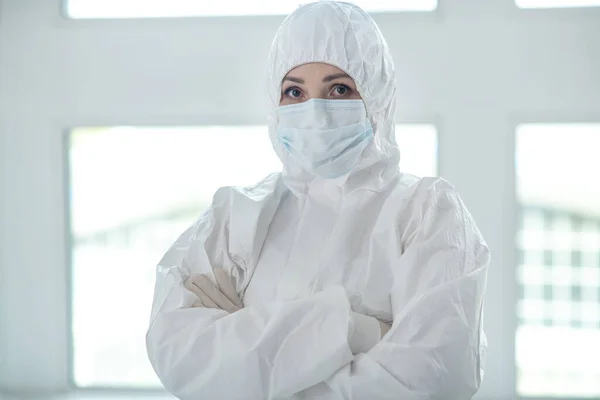Медичний працівник у захисному одязі та медичній масці, що стоїть зі складеними руками — стокове фото