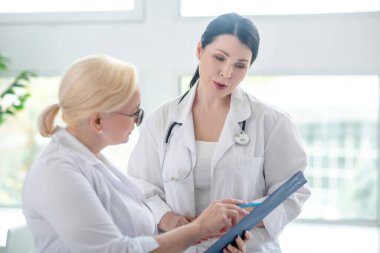 İki kadın doktor tıbbi geçmişi okuyor ve ilgileniyorlar.