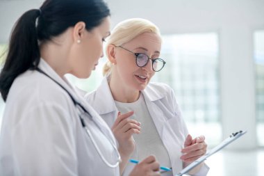 İki kadın doktor tıbbi geçmişi okuyor ve araştırıyor.