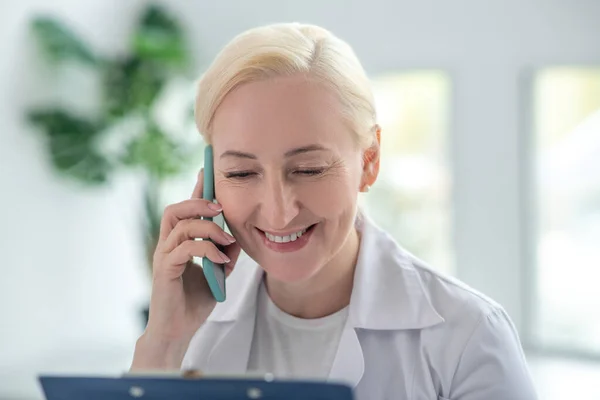 Блондинка лікар посміхається і розмовляє з пацієнтом — стокове фото