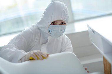 Koruyucu iş kıyafetleri içinde ev dezenfeksiyonu yapan kişi