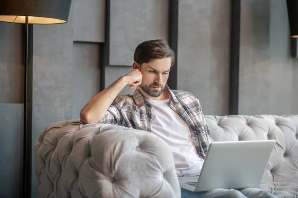 Man on a couch looking at a laptop screen — Stock Photo, Image