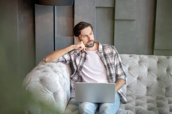 Pensive handsome man with a laptop looking to the side. — Stock Photo, Image