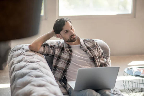 Man liggande på en soffa med en bärbar dator — Stockfoto