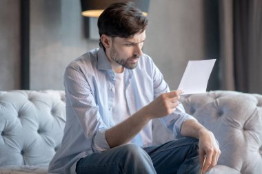 Elindeki belgelerle kaşlarını çatan özenli bir adam..