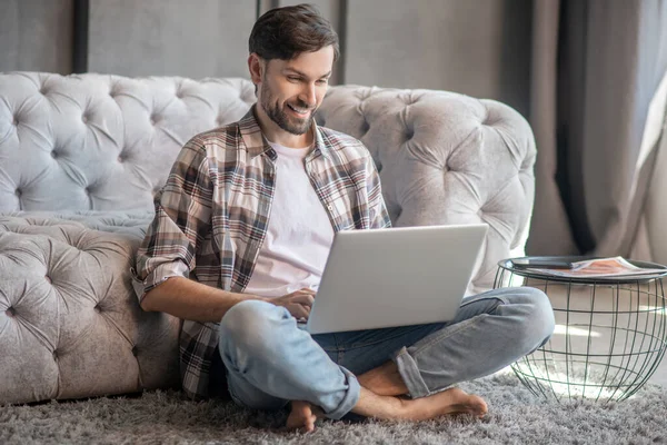 Homem descalço sentado no chão com um laptop — Fotografia de Stock