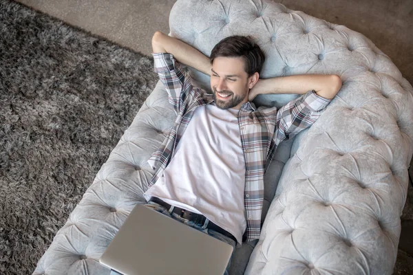 Exitoso hombre guapo relajándose en casa en el sofá . —  Fotos de Stock