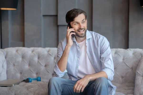 Jeune homme assis sur un canapé avec un smartphone . — Photo