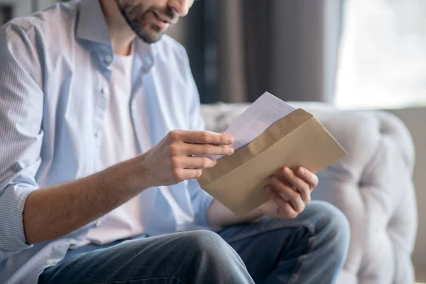 Manos masculinas sacando una carta de un sobre de papel . — Foto de Stock