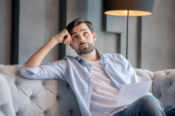 Denkende trieste man zittend met een document in zijn hand. — Stockfoto