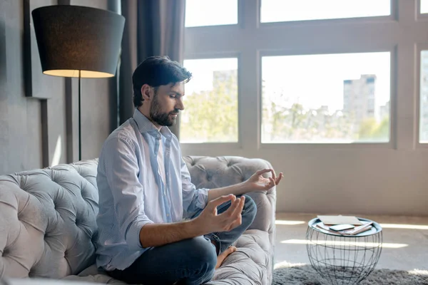 Lindo hombre tranquilo sentado en una pose en el sofá . —  Fotos de Stock