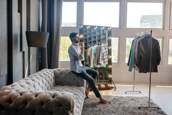 Молодой взрослый босиком мужчина смотрит на свой гардероб . — стоковое фото
