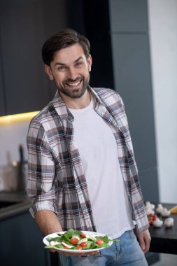 Bir tabak sebze salatasıyla neşeli bir adam.
