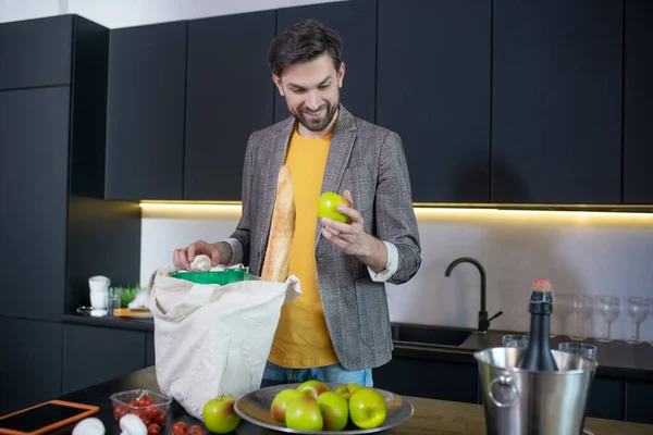 Joven barbudo sosteniendo una manzana verde y sonriendo — Foto de Stock