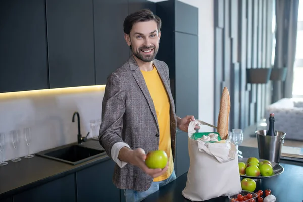 Jonge man met een baard met een appel en een glimlach — Stockfoto