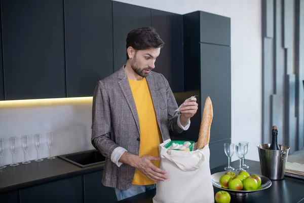 Jonge man met een baard die de rekening van de winkel in zijn hand houdt — Stockfoto