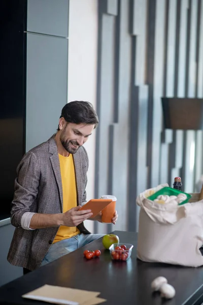 Усміхнений чоловік тримає комп'ютерний планшет і келих кави . — стокове фото