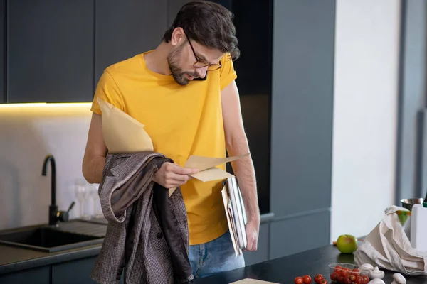 Homem de óculos com papéis falando em um smartphone . — Fotografia de Stock