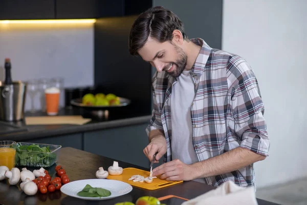 Jovem adulto com barba cozinhando em casa . — Fotografia de Stock