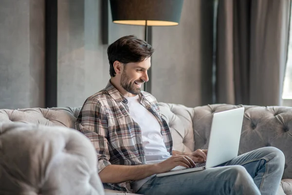 Young adult man with laptop on the couch. — Stock Photo, Image