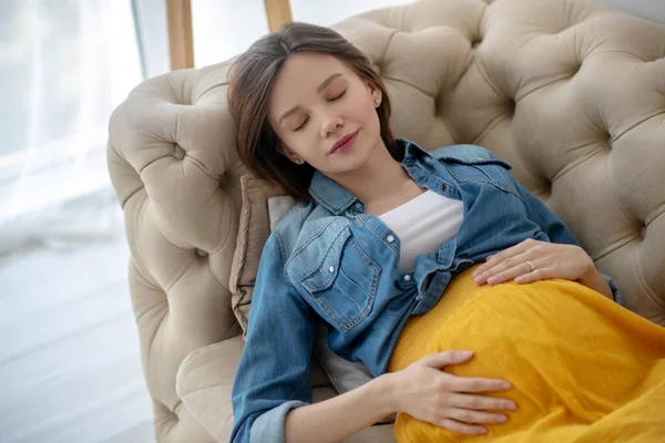 若いです妊娠中の女性でAジーンズジャケット昼寝 — ストック写真