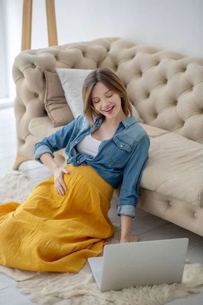 Ung gravid kvinna i jeans jacka med en videochatt — Stockfoto